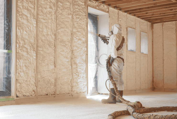 un homme isole un mur avec l'isolation projetée